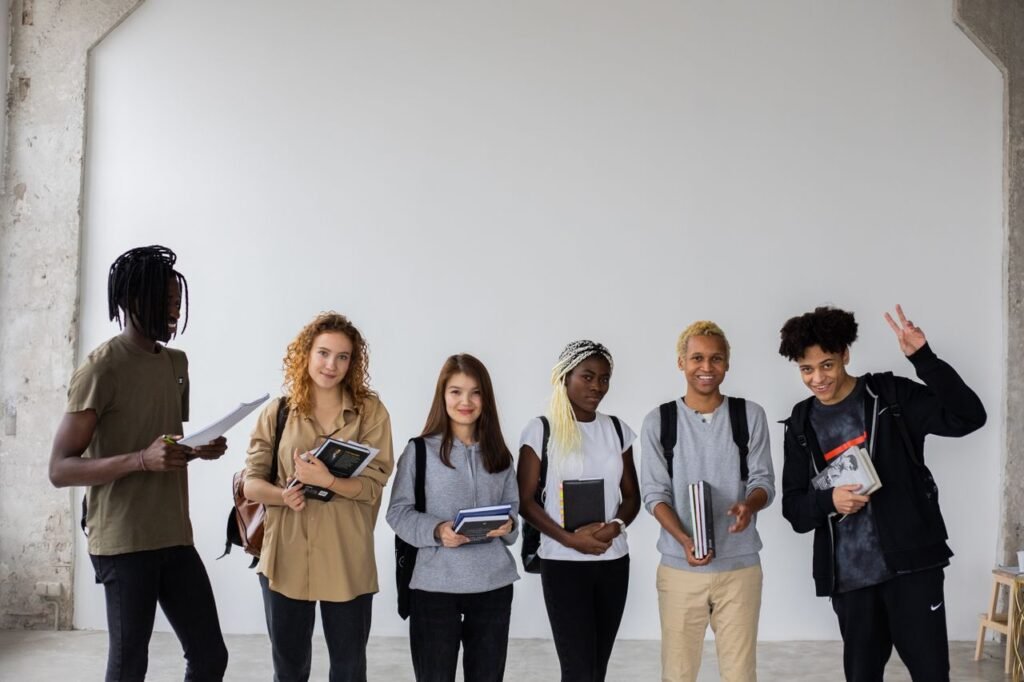 Group of African American man showing peace gesture while standing with diverse classmates holding documents and notebooks